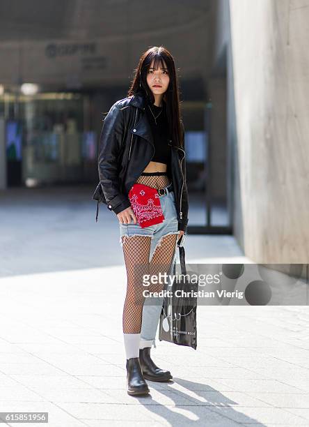 Korean model Jeong San ho wearing a black leather jacket, cropped top, red banda, a ripped denim jeans, net tights on October 20, 2016 in Seoul,...