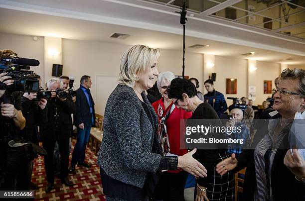 Marine Le Pen, leader of the French National Front, greets an attendee at a party debate in Paris, France, on Thursday, Oct. 20, 2016. Once seen as...