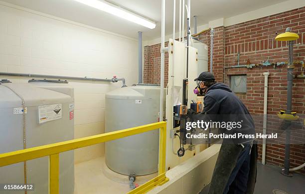 Randy Nichols checks the feed rate of hydrofluorosilicic acid, a type of fluoride in tanks at left, as it is added to water at the Kennebunk,...