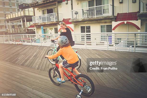 mother and son riding bicycles on the boardwalk. - long beach new york stock pictures, royalty-free photos & images