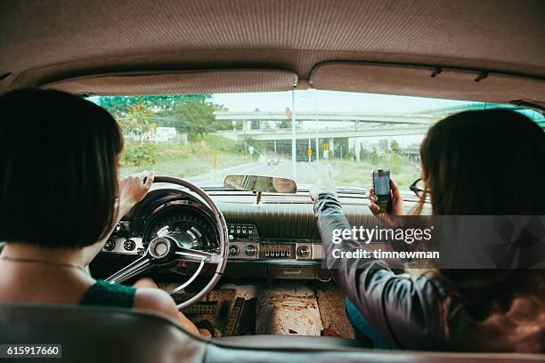 road trip women in vintage american car and phone gps - old car interior stock pictures, royalty-free photos & images