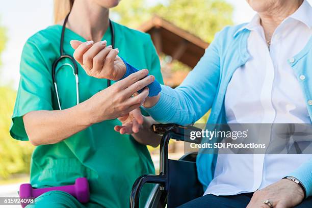 nurse helping an injured senior woman in a wheelchair - wound care stock pictures, royalty-free photos & images