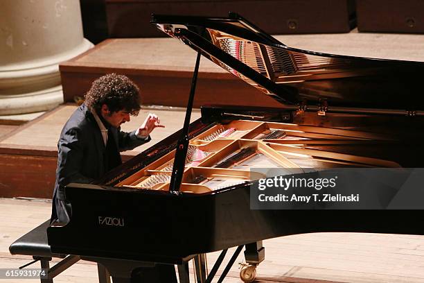 Italian pianist Federico Colli raises his hand as he performs a solo piano recital on a Fazioli grand with works by composers Mozart, Beethoven,...