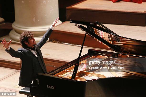 Italian pianist Federico Colli raises his hands to pause as he performs a solo piano recital on a Fazioli grand with works by composers Mozart,...