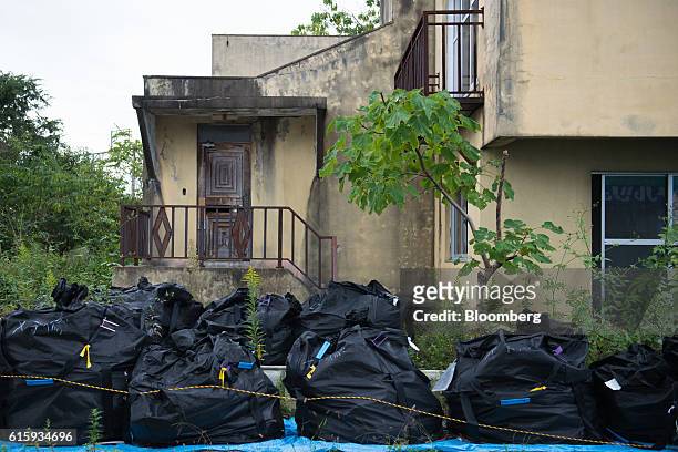 Bags of nuclear waste sit in front of an abandoned house in Namie, Fukushima Prefecture, Japan, on Wednesday, Oct. 5, 2016. Namie, one of the...