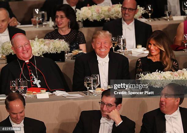 Cardinal Timothy Dolan sits between and his wife Melania Trump, Donald Trump attends the annual Alfred E. Smith Memorial Foundation Dinner at the...