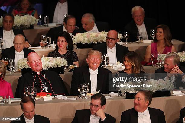 Cardinal Timothy Dolan sits between and his wife Melania Trump, Donald Trump attends the annual Alfred E. Smith Memorial Foundation Dinner at the...