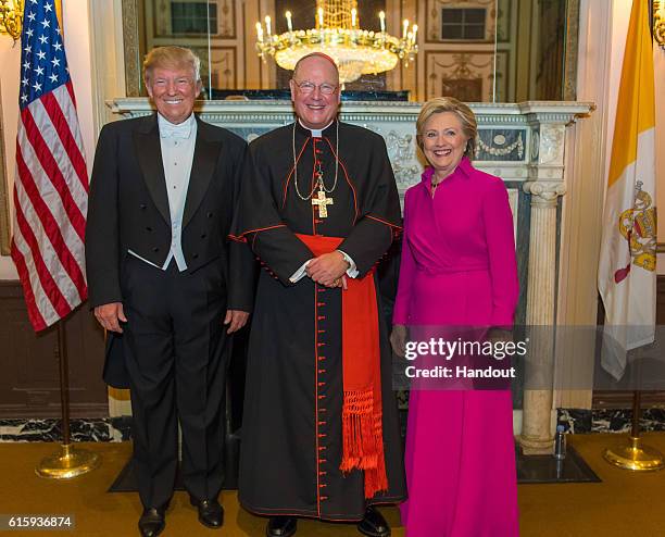 In this handout provided by the Archdiocese of New York, Cardinal Timothy Dolan poses with Republican presidential candidate Donald Trump and...