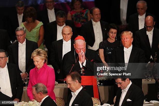 Cardinal Timothy Dolan stand between, Hillary Clinton and Donald Trump participate in a prayer while attending the annual Alfred E. Smith Memorial...