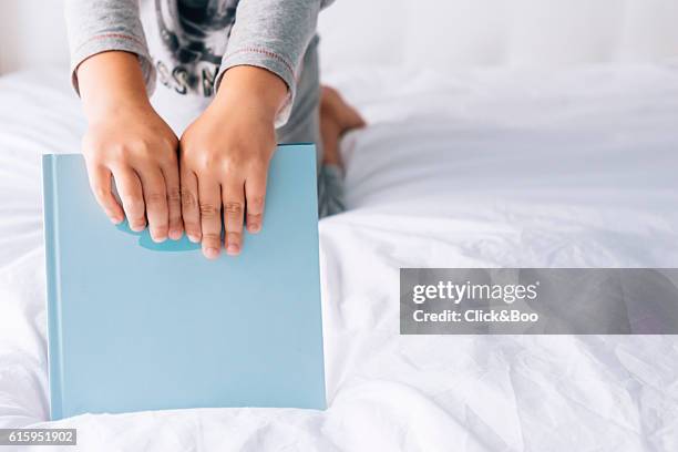 close up boy holding a blue book - baby close up bed photos et images de collection