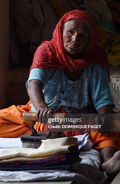 In this photograph taken on October 12 laundry worker Gauri Devi irons clothes at an open-air laundry facility or "dhobi ghat" in New Delhi. Over the...