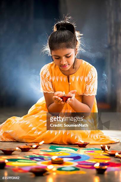 young girl making rangoli, decorating with oil lamps for diwali - rangoli stock pictures, royalty-free photos & images