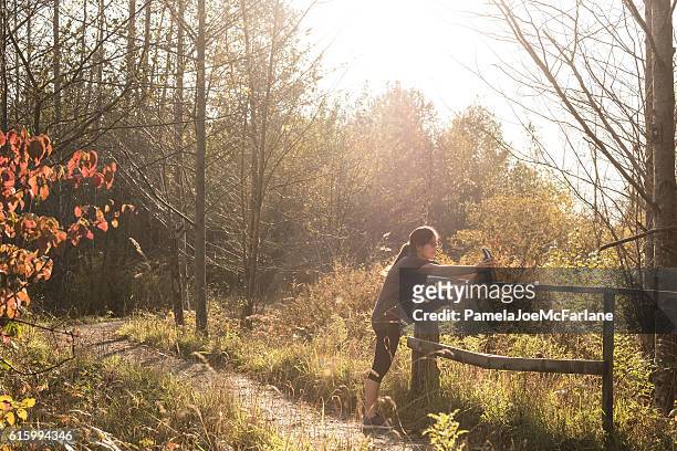 teenaged female jogger stretching leg after running on rural path - leg stretch girl stock pictures, royalty-free photos & images