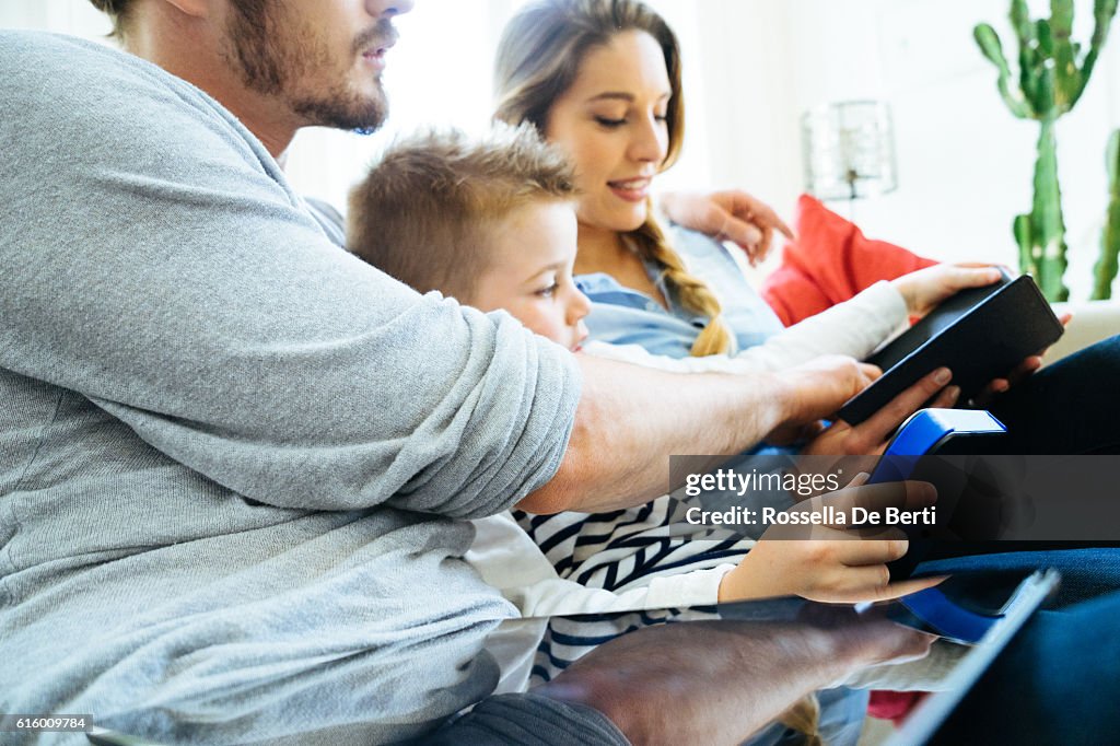 Cheerful Young Family Using Technology Together In The Living Room
