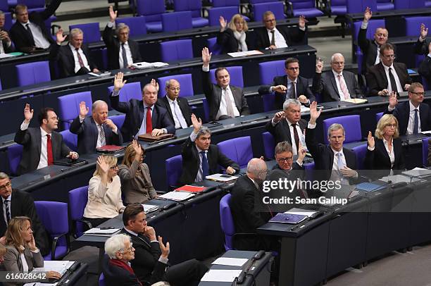 Members of the Bundestag raise their hands in the vote to approve a new law that will expand the legal framework in which Germany's Federal...