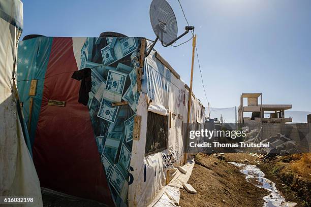 Bar Elias, Lebanon An old advertising poster, printed with banknotes, serves as a tarp for a tent in a refugee camp in the Bekaa plain on October 06,...