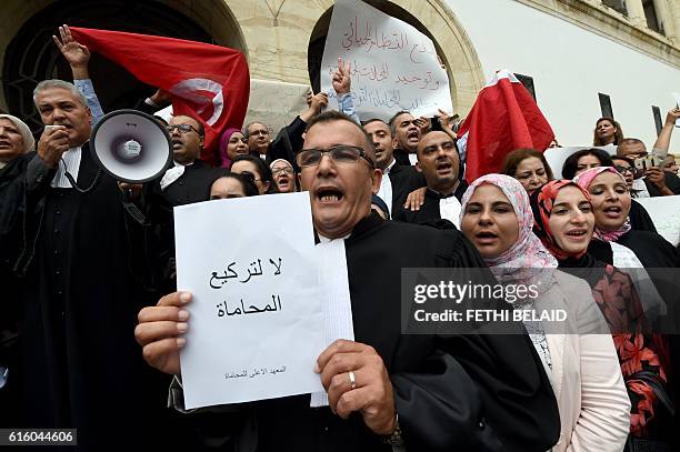 Tunisian lawyer holds a placard reading in Arabic "do not let lawyers go down on bended knees" during a protest outside Tunis law court against the...