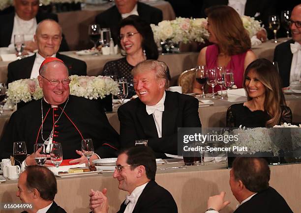 Sitting between Cardinal Timothy Dolan and his wife Melania Trump, Donald Trump attends the annual Alfred E. Smith Memorial Foundation Dinner at the...