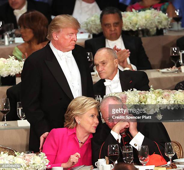 Cardinal Timothy Dolan speaks with Hillary Clinton as Donald Trump walks by at the annual Alfred E. Smith Memorial Foundation Dinner at the Waldorf...