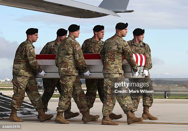 Army carry team moves the transfer case containing the remains of U.S. Army Sgt. Douglas J. Riney, during a dignified transfer at Dover Air Force...