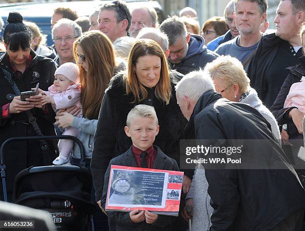 Mackenzie Robertson, aged 11, holds a school project on the disaster as he waits to see Prince Charles, Prince of Wales outside the memorial garden,...