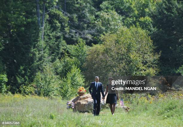 President Barack Obama and First Lady Michelle Obama walk hand in hand on September 11, 2011 as they visit the crash site after attending in a...