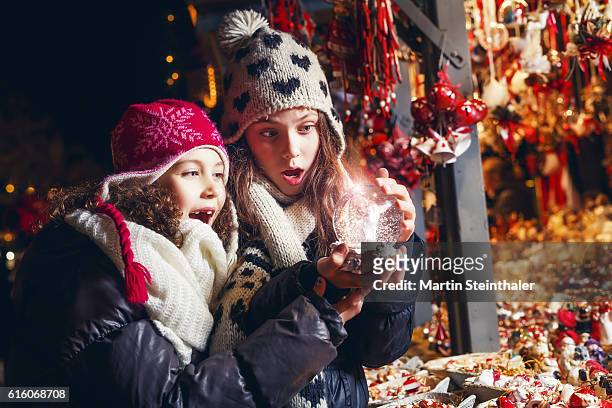 surprised girls looking into the crystal ball - christkindlmarkt stock-fotos und bilder
