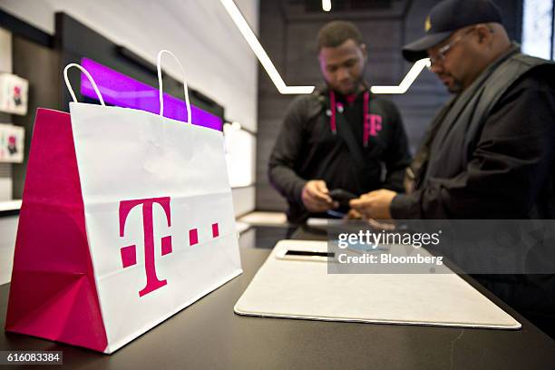 Bag sits on a counter as an employee assists a customer at a T-Mobile US Inc. Store in Chicago, Illinois, U.S., on Friday, Oct. 21, 2016. T-Mobile US...