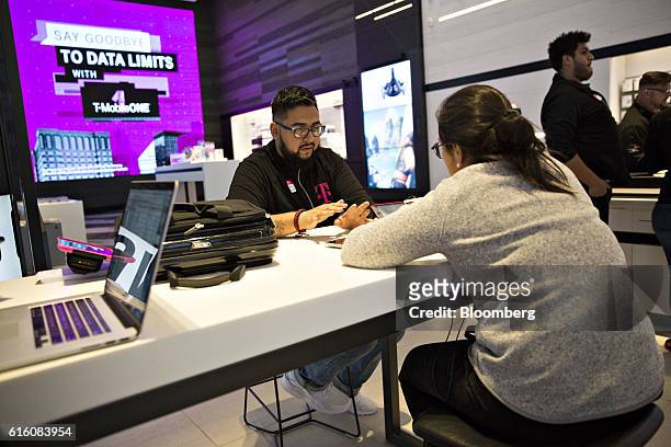 An employee assists a customer at a T-Mobile US Inc. Store in Chicago, Illinois, U.S., on Friday, Oct. 21, 2016. T-Mobile US Inc. Is scheduled to...