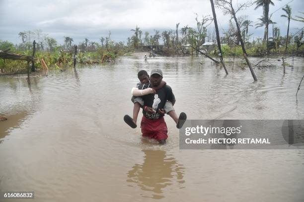 Men carries his son across an area flooded by rains from a tropical storm, after the passing of Hurricane Matthew earlier in the month, in the...