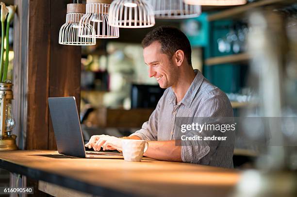 hombre trabajando en línea en un café - cafe owner fotografías e imágenes de stock