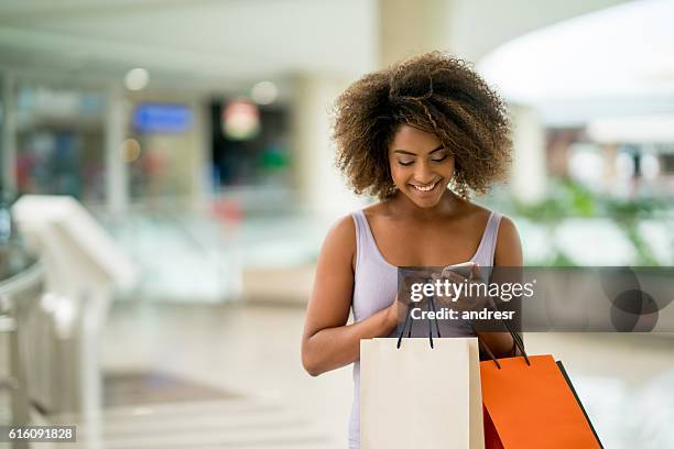 compras mujer enviando mensajes de texto en su teléfono - shopping mall fotografías e imágenes de stock