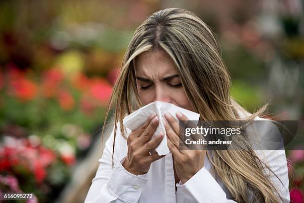 woman sneezing at a greenhouse - spring allergies stock pictures, royalty-free photos & images