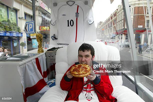 Gareth Howard takes a bite from his first Goodfella's Pizza as he starts his campaign to spend the entire World Cup in a perspex box on the back of a...