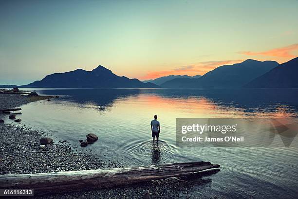 male traveller standing in water watching sunset - beach top view stock-fotos und bilder