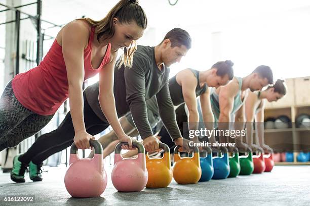 clase de gimnasia haciendo flexiones en kettlebells - kettle bells fotografías e imágenes de stock
