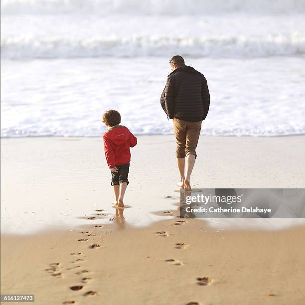 a 5 years old boy and his dad on the beach - boy barefoot rear view stock-fotos und bilder