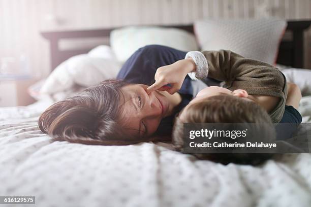 a mum playing with her son on a bed - family on bed stock-fotos und bilder