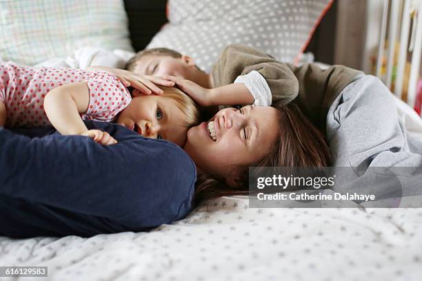 a mum playing with her children on a bed - family on bed stock-fotos und bilder