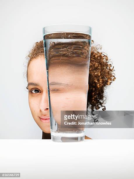 portrait of female through glass of water - mirar a través fotografías e imágenes de stock