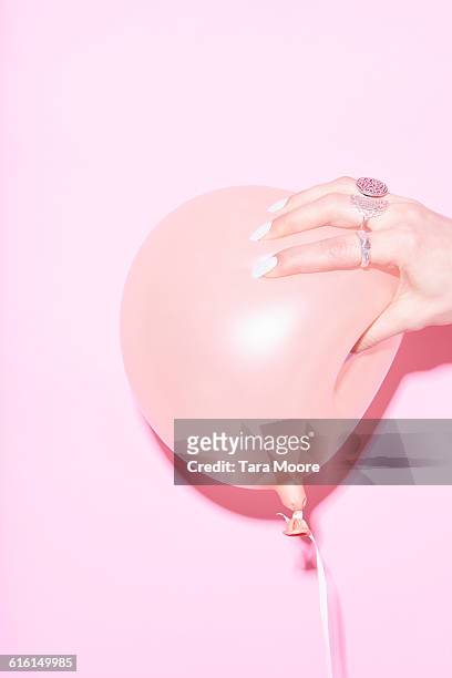 hand squeezing pink balloon - blowing up balloon stock-fotos und bilder