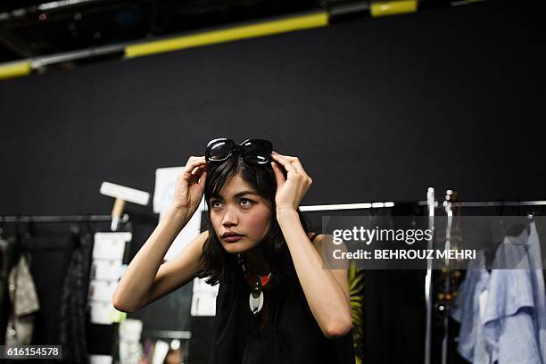 In this picture taken on October 17 Japanese model Rina Fukushi checks her looks in the mirror in back stage of a show by Japanese designer Tae...