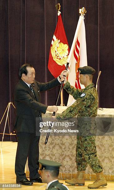 Japan - Japanese Defense Minister Yasuo Ichikawa hands a flag to a member of the Ground Self-Defense Force at the Defense Ministry in Tokyo on Jan. 7...