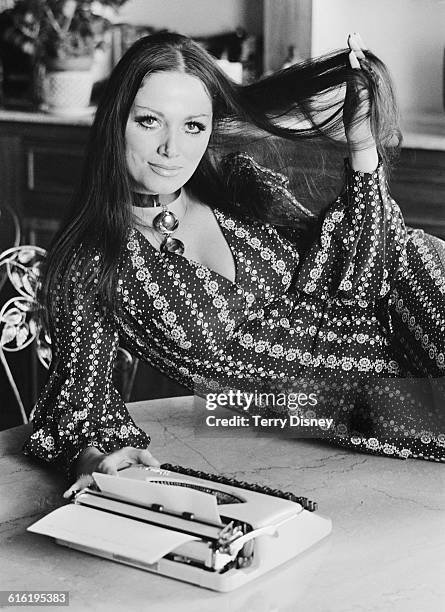 English novelist Jackie Collins poses with a typewriter, UK, 22nd March 1971.