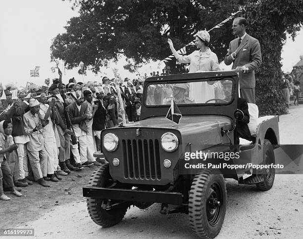 Queen Elizabeth II and Prince Philip, Duke of Edinburgh wave to Gurkha ex-servicemen and residents of a Gurkha village from the rear of a Willys MB...