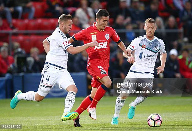 Sergio Guardiola of Adelaide United competes for the ball with Nicholas Ansell and Oliver Bozanic of the Victory during the round three A-League...