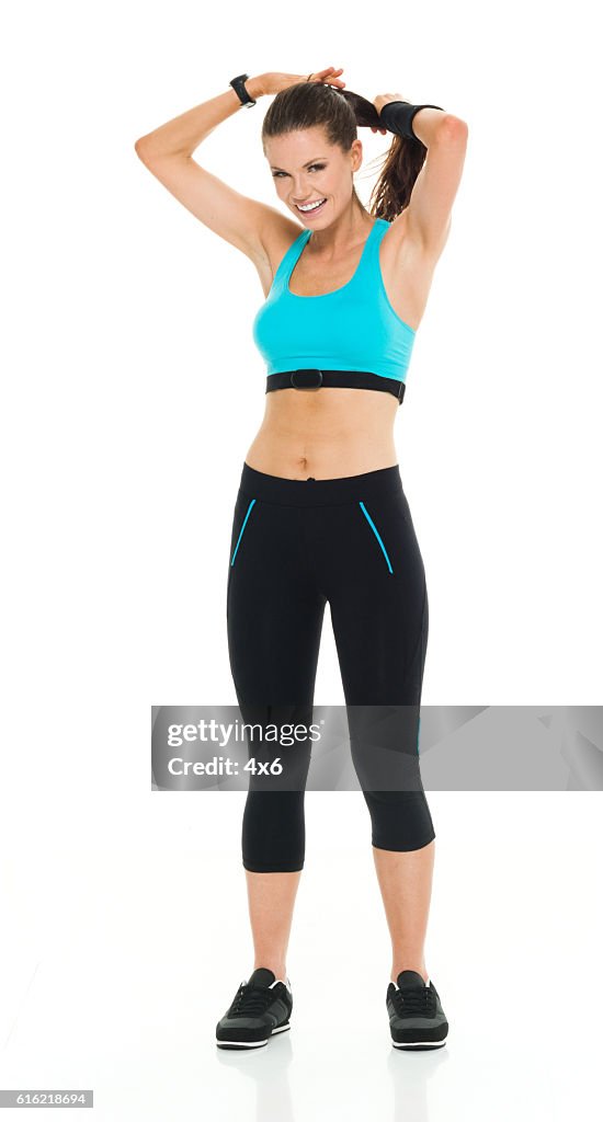 Smiling female runner tying her hair