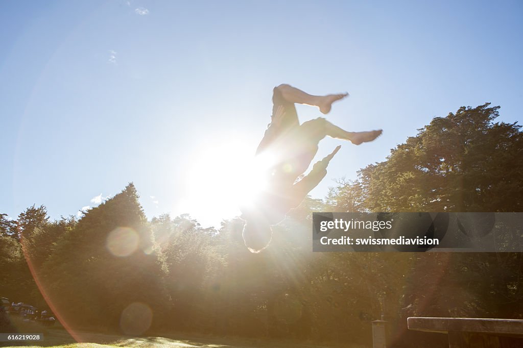 Young man jumps mid-air against blue sky