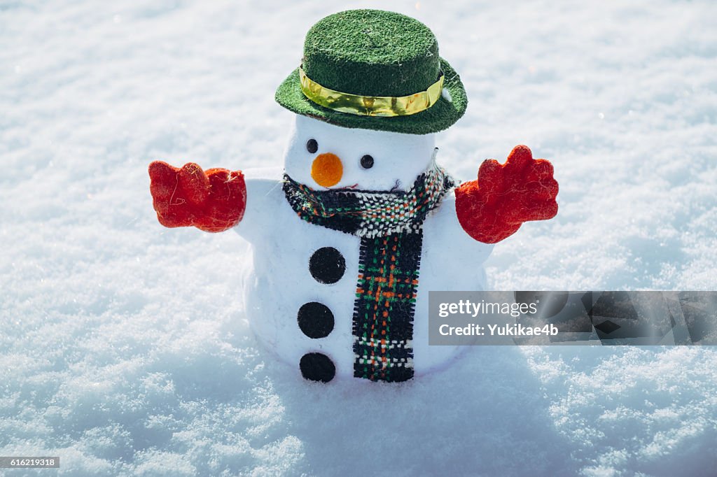 Snow man stand among pile of snow.