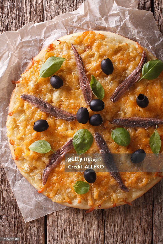 French pizza Pissaladiere close-up on the table. vertical top view